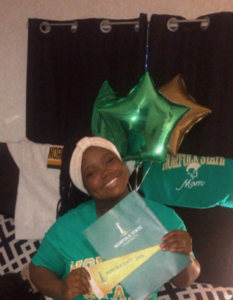 Portrait of Aniyah, a Black woman smiling looking directly at the camera, holding college acceptance letter