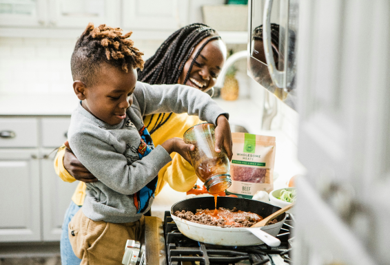Black mother and son in front of stove cooking